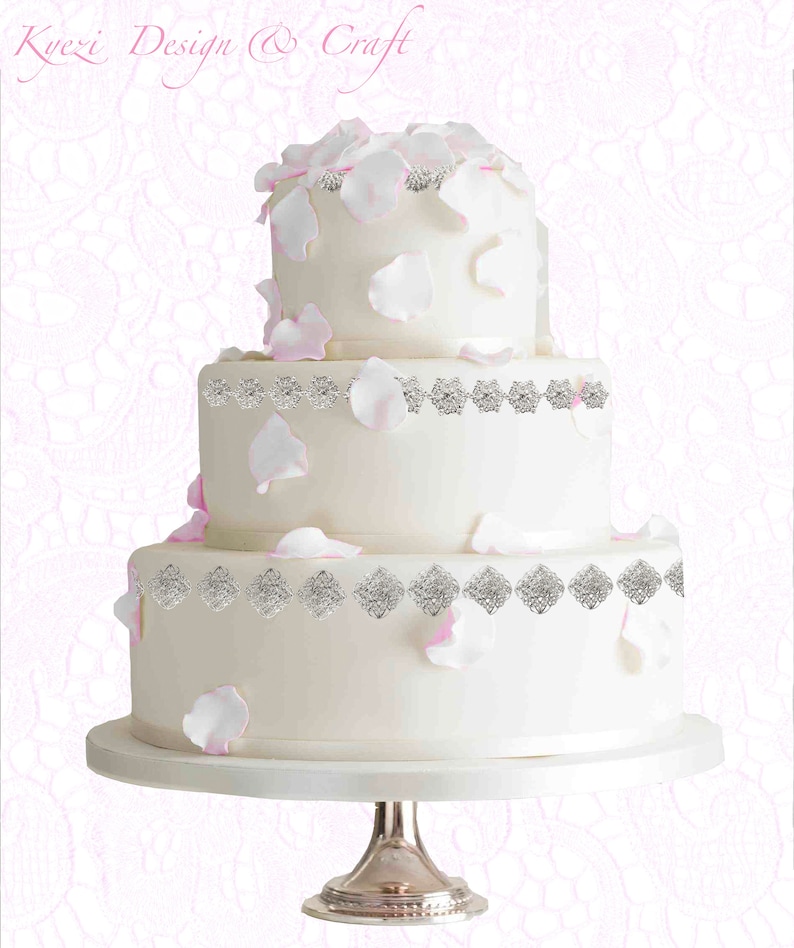May include: A three-tiered white wedding cake decorated with silver embellishments and pink rose petals.