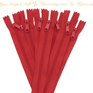 May include: A bundle of ten red zipper closures, each with a metal slider. The zippers are arranged in a fan shape, with the sliders facing outward.
