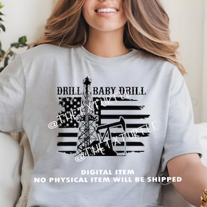 Könnte beinhalten: Ein graues T-Shirt mit einer schwarz-weißen Grafik einer Ölplattform und einer amerikanischen Flagge. Der Text "Drill Baby Drill" ist auf dem T-Shirt aufgedruckt. Der Text "Digitaler Artikel" und "Kein physischer Artikel wird versandt" ist ebenfalls auf dem T-Shirt aufgedruckt.