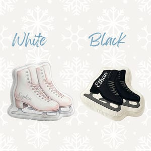 May include: Two decorative ice skate pillows, one white and one black, against a snowflake background. The white pillow has the name "Sophia" and the black pillow has the name "Ethan". The word "White" and "Black" are written above the pillows.