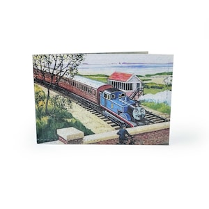 May include: A wallet featuring a colorful illustration of Thomas the Tank Engine. The image shows Thomas pulling a train along a track, with a coastal scene in the background. The wallet is made of a sturdy material.