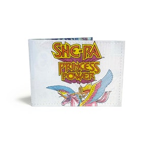 May include: White wallet featuring the She-Ra Princess of Power logo in orange, yellow, and purple. The wallet also displays a graphic of She-Ra riding a winged unicorn with pink, blue, and yellow accents. The wallet is closed.
