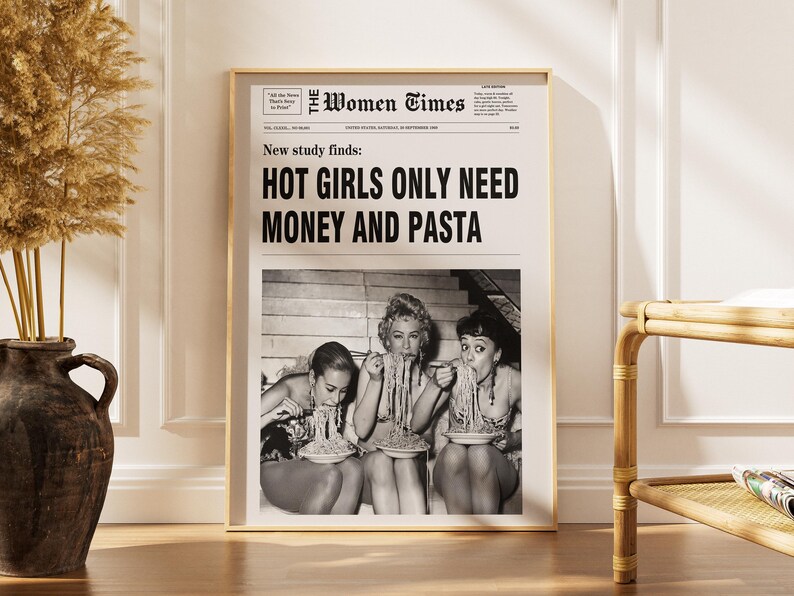 以下が含まれることがあります： The Women Timesというタイトルの白黒新聞レイアウトが印刷された額入りポスター。見出しには「New study finds: HOT GIRLS ONLY NEED MONEY AND PASTA」と書かれています。その下には、パスタを食べている3人が写った白黒写真があります。
