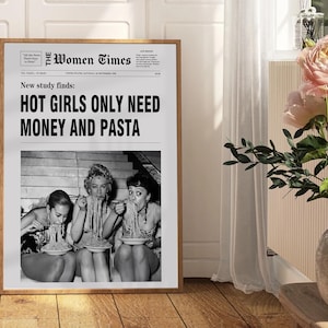 以下が含まれることがあります： The Women Timesというタイトルの額入りアートプリント。見出しは「New study finds: HOT GIRLS ONLY NEED MONEY AND PASTA」。テキストの下には、階段に座ってボウルからパスタを食べている3人の白黒写真が印刷されています。