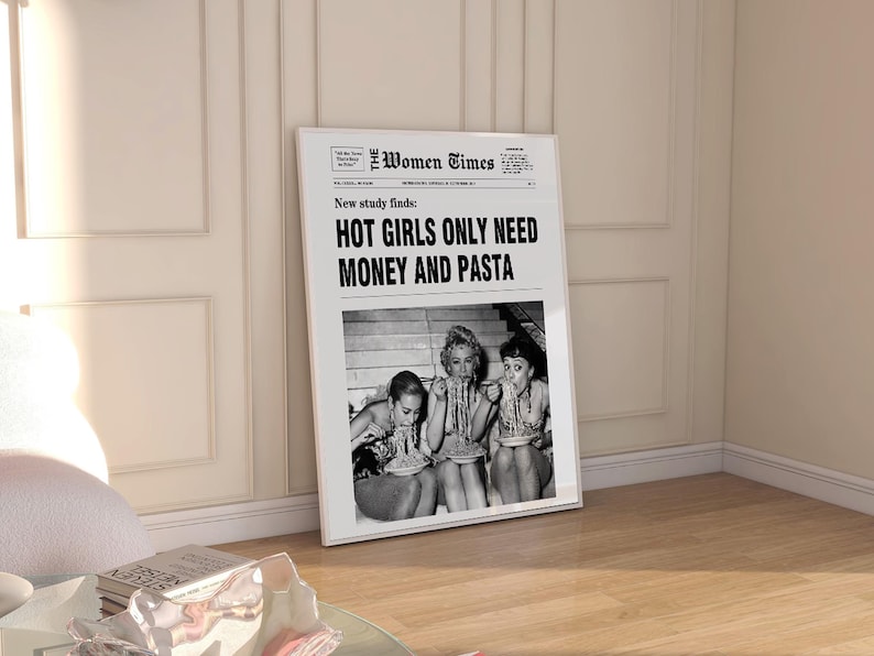 以下が含まれることがあります： The Women Timesというタイトルの白黒新聞デザインが施された額入りポスター。見出しには「New study finds: HOT GIRLS ONLY NEED MONEY AND PASTA」と書かれています。テキストの下には、パスタを食べている3人の白黒写真があります。