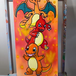 Op de afbeelding: Een verticaal canvas schilderij met drie oranje en rode vuurwezens die verticaal op elkaar zijn gestapeld. De achtergrond is een verloop van geel, oranje en rood met zachte, gloeiende cirkelvormige vlekken. Het onderste wezen is klein, het middelste is groter en rood, en het bovenste is een groot oranje wezen met blauwgroene vleugels.