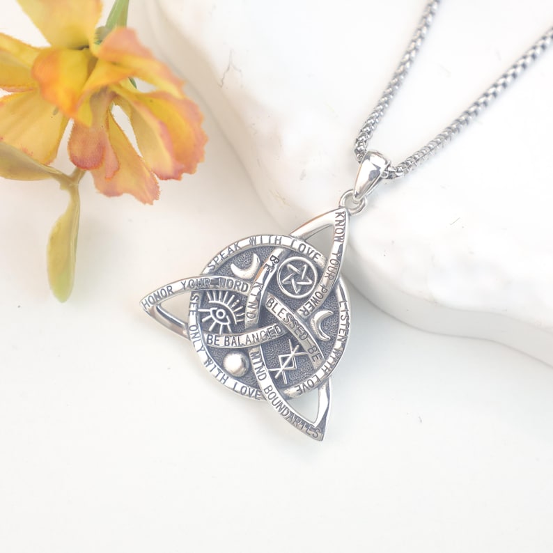 May include: A silver-toned pendant necklace featuring a triquetra shape with engraved text including "Speak with love," "Honor your word," "Be kind," "Blessed be," "Know your power," "Listen with love," "Mind boundaries," and "See only with love."