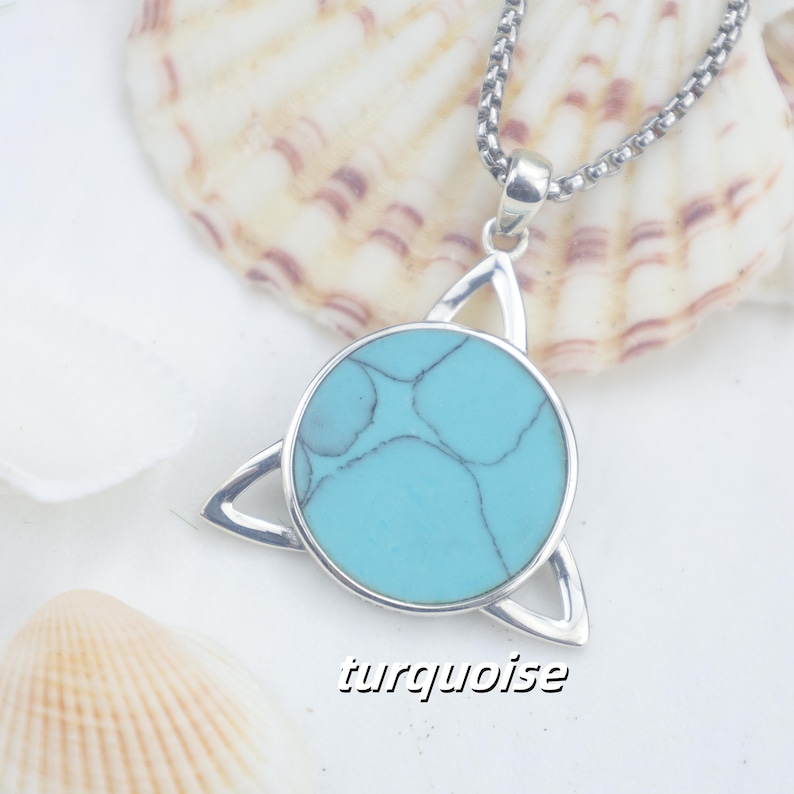 May include: A silver-toned pendant necklace featuring a circular turquoise stone with dark veining, set within a triangular metal frame. The pendant hangs from a silver-toned box chain. The word turquoise is printed in black text at the bottom.