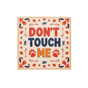 May include: Square, cream-colored decorative cloth with the words "DON'T TOUCH ME" in red, blue, and orange. The design includes paw prints, floral and leaf motifs, and a decorative border.