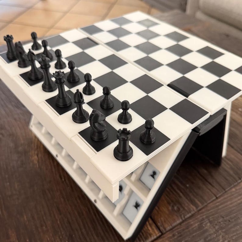 Puede incluir: Un juego de ajedrez blanco y negro con piezas negras. El tablero de ajedrez est&aacute; configurado con las piezas en sus posiciones iniciales. El tablero de ajedrez est&aacute; sobre un marco blanco con una base negra.