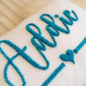 Cojín personalizado con nombre de aguja perforadora: Adalie, con detalle de corazón en texto cursivo. Cojín personalizado hecho a mano para habitación de niña o regalo de bebé.