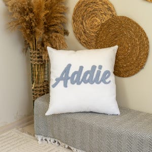 Cojín con nombre personalizado: diseño de Addie bordado a mano en hilo azul sobre tela blanca. Regalo suave y personalizado para habitación de bebé o infantil.