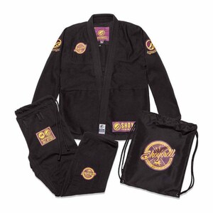 Puede incluir: Un conjunto de uniforme de artes marciales negro, que incluye una chaqueta, pantalones y una bolsa con cordón. El uniforme presenta parches bordados dorados y morados con el texto "Shoyoroll". La chaqueta y los pantalones están extendidos, y la bolsa está de pie.