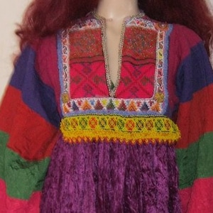 May include: A long-sleeved, purple dress with colourful striped sleeves and intricate embroidery around the neckline. The dress has a gathered skirt and a V-neck.