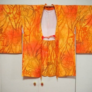 May include: A traditional Japanese kimono with a vibrant orange and yellow floral pattern. The kimono is made of a lightweight fabric and has a relaxed fit.