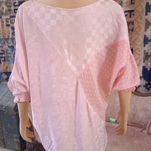 Könnte beinhalten: Eine rosa-weiße gemusterte Bluse mit einem karierten Muster auf der oberen Hälfte und einem Tupfenmuster auf der unteren Hälfte.