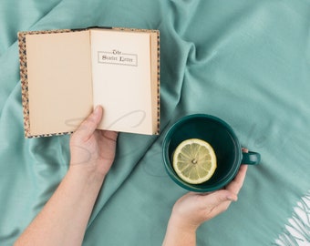 Hand holding book with a cup of tea Stock Image