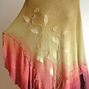 Puede incluir: Un poncho de punto con un degradado de amarillo, naranja y rojo. El poncho tiene un dise&ntilde;o floral con hojas y flores bordadas.