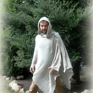 K&ouml;nnte beinhalten: Eine Person tr&auml;gt einen hellgrauen Kapuzenponcho mit einem langen, flie&szlig;enden Design. Der Poncho ist aus einem weichen, strukturierten Stoff gefertigt. Die Person steht vor einem gr&uuml;nen Baum.