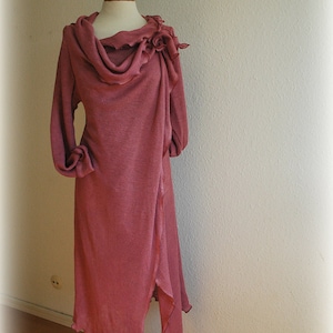 May include: A long, dusty rose colored, knitted wrap dress with a cowl neck and a flower detail on the shoulder.