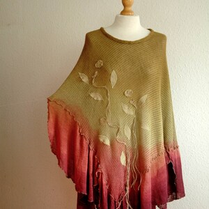 Puede incluir: Un poncho de punto de color verde y rojo degradado con un dise&ntilde;o floral. El poncho tiene un dobladillo con volantes y se muestra en un maniqu&iacute;.