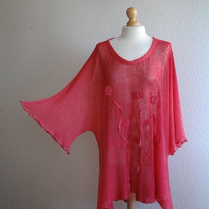 Puede incluir: Una blusa ligera y fluida de color coral, transparente, de corte holgado. La blusa presenta delicados bordados florales y un dobladillo ligeramente asim&eacute;trico.