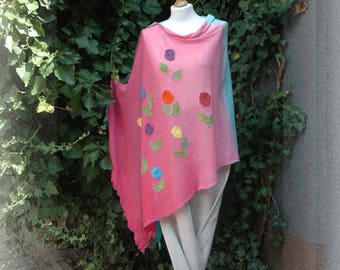 May include: A pink and blue ombre poncho with a crocheted flower design. The poncho is displayed on a wooden stand.