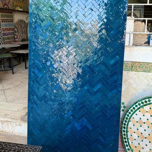 May include: A large, rectangular wall panel featuring a blue herringbone tile design. The tiles shift from a lighter blue at the top to a deep blue at the bottom. The panel is displayed in a shop setting, likely for sale.