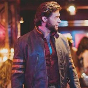 Può includere: Giacca di pelle marrone con strisce arancioni sulle maniche e finiture arancioni. La giacca è indossata sopra una camicia rossa abbottonata e jeans blu. La giacca ha una chiusura con cerniera.