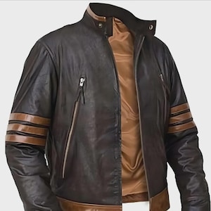 May include: A black leather jacket with brown detailing. The jacket has a stand-up collar, two zipped pockets, and brown stripes on the sleeves. The inner lining is a light brown colour.