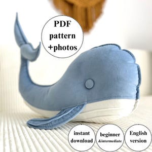 May include: A soft, blue whale cushion with a white underside and a button eye. The image includes text that says "PDF pattern + photos", "instant download", "beginner & intermediate", and "English version".