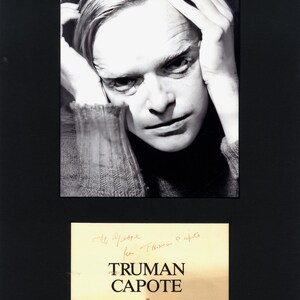 Könnte beinhalten: Ein Schwarz-Weiß-Porträt von Truman Capote mit den Händen am Kopf und einer Zigarette, montiert über einer rechteckigen Plakette mit dem Text TRUMAN CAPOTE at LINCOLN CENTER und handschriftlichem Text auf schwarzem Hintergrund.
