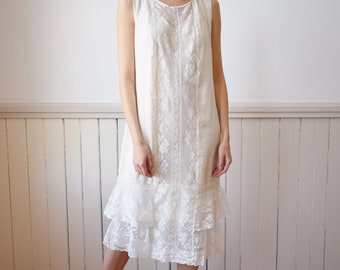 May include: A white lace dress with a ruffled hem and a pearl headband. The dress is sleeveless and has a fitted bodice.