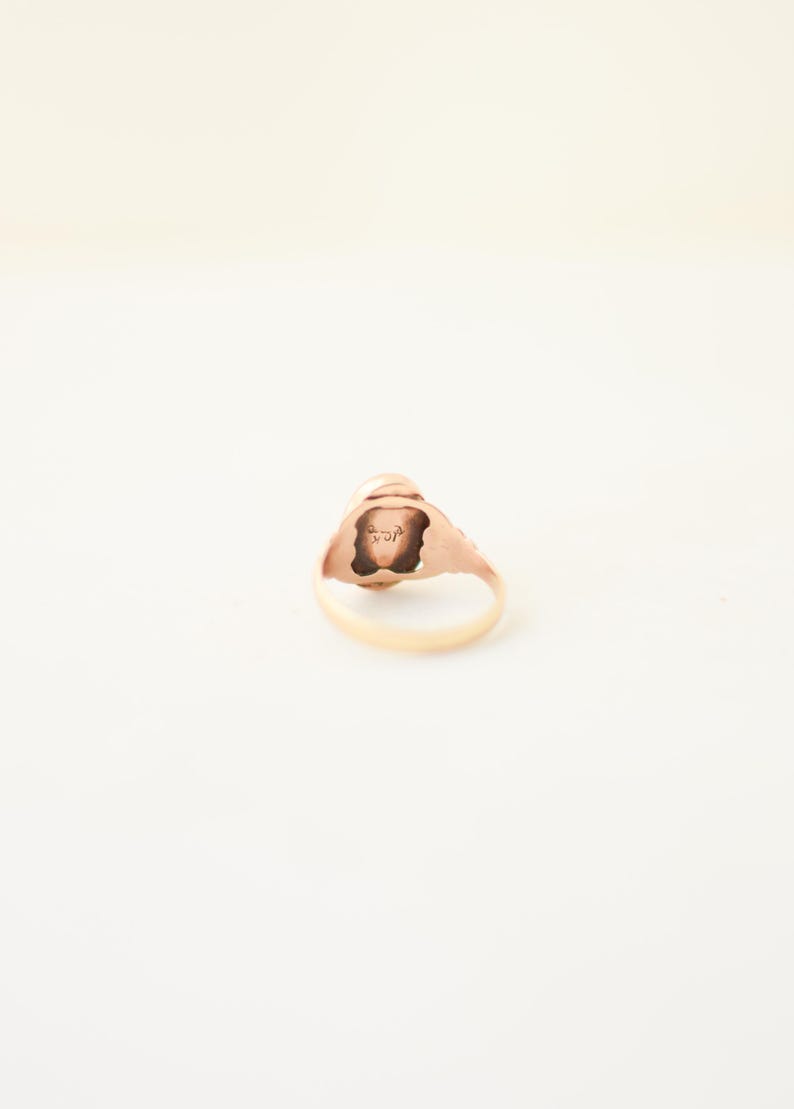 Op de afbeelding: Een gouden ring met een gladde, ronde band en een centrale zetting. De binnenkant van de ringband is duidelijk gestempeld met de tekst 10K, wat de zuiverheid van het goud aangeeft. Het metaal heeft een warme, gepolijste afwerking.
