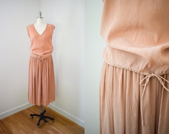 May include: A peach-colored sleeveless dress with a drawstring waist and a flowing skirt.