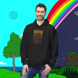 May include: A black hooded sweatshirt featuring a Mona Lisa parody wearing an orange hat. The sweatshirt has a front pocket and is worn by a person in blue jeans. The background includes a rainbow and cartoon landscape.