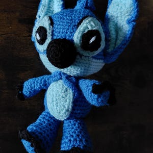 Puede incluir: Mu&ntilde;eco Stitch azul hecho a mano con ganchillo y detalles en azul claro. El mu&ntilde;eco tiene grandes ojos negros, una nariz negra y garras negras. Las orejas son grandes y est&aacute;n erguidas. Es un personaje popular de Disney.