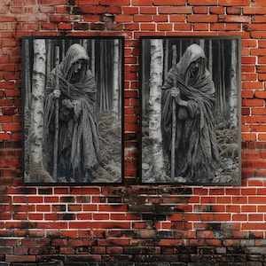 May include: Two framed black and white prints of a cloaked figure in a forest setting. The figure holds a staff and appears to be walking. The prints are mounted on a red brick wall.
