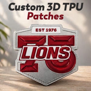 Op de afbeelding: Een aangepaste 3D TPU-patch met een schildontwerp. De patch bevat het woord "LIONS" in het wit, met het nummer "75" in het rood. De tekst "EST 1976" is ook aanwezig. De patch heeft een zilveren rand en een getextureerde achtergrond.