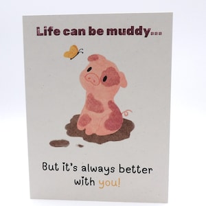 May include: A rectangular greeting card with a white background featuring a pink pig with darker pink spots sitting in a brown mud puddle. A small yellow butterfly flies above the pig. The text reads: Life can be muddy... But it's always better with you!