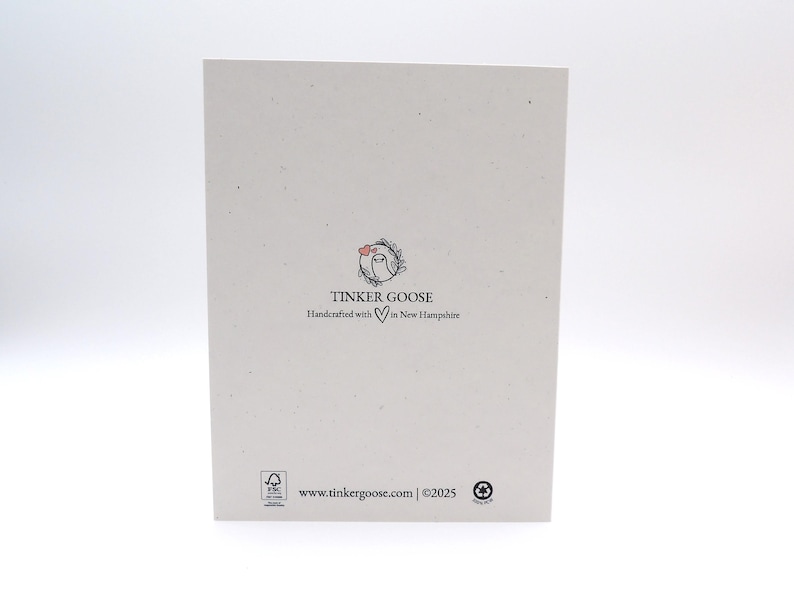 May include: A rectangular off-white card featuring a small circular logo with a goose and a heart. Below the logo, the text reads TINKER GOOSE Handcrafted with a heart symbol in New Hampshire. The bottom includes a website URL and copyright 2025.