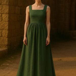 May include: A long, sleeveless green dress with a square neckline and a fitted bodice. The skirt is gathered and flows to the floor. The dress is made of a solid, textured fabric.