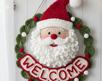 May include: Crocheted Christmas wreath featuring Santa Claus with a red hat and white beard. The wreath includes a green leaf design, red and white accents, and a banner that reads "WELCOME".