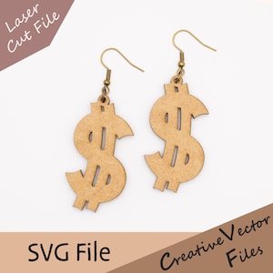 Puede incluir: Un par de pendientes de madera con forma de signo de dólar, con ganchos dorados. Los pendientes son de color marrón claro y tienen un diseño cortado con láser. La imagen también incluye el texto "Laser Cut File", "SVG File" y "Creative Vector Files".
