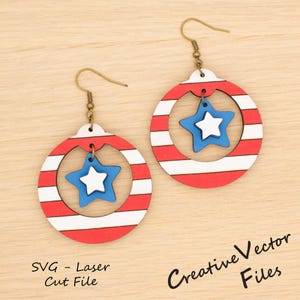 May include: A pair of patriotic earrings featuring a red and white striped circular design with a blue and white star pendant. The earrings have gold-colored hooks. The text "SVG - Laser Cut File" and "Creative Vector Files" are visible.
