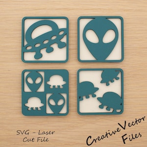 May include: Four teal and white square coasters with alien and UFO designs. The coasters feature cut-out designs of alien heads and flying saucers. The text "SVG - Laser Cut File" and "Creative Vector Files" are visible.
