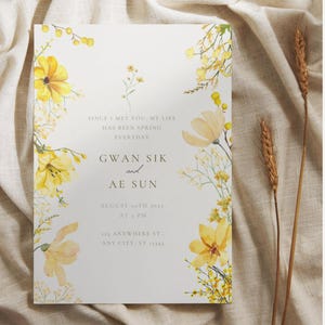 May include: A white invitation card with yellow floral watercolor designs. The card includes text that reads "SINCE I MET YOU, MY LIFE HAS BEEN SPRING EVERYDAY GWAN SIK and AE SUN AUGUST 20TH 2023 AT 5 PM 123 ANYWHERE ST., ANY CITY, ST 12345."