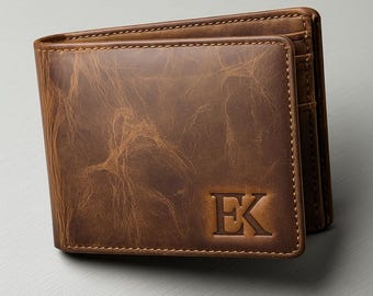 May include: Brown leather wallet with the initials "EK" embossed on the front. The wallet has a textured appearance and visible stitching around the edges. The wallet is a bi-fold style.