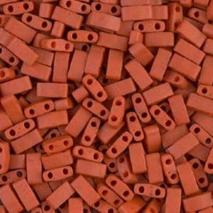 Può includere: Un mucchio di piccole perline rettangolari arancioni, ciascuna con due fori. Le perline sono di dimensioni e forma uniformi, disposte in modo casuale. Adatte per la creazione di gioielli e lavori artigianali.