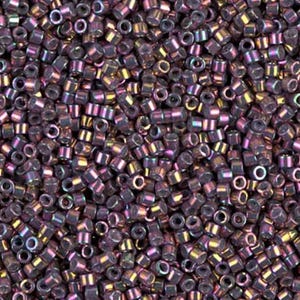 May include: Close-up of a pile of small, cylindrical beads. The beads are a dark purple color with an iridescent sheen, reflecting hues of gold, pink, and blue. The beads are tightly packed together, filling the frame.